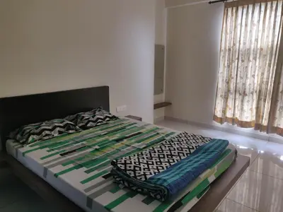 a bed sitting in a room with a window at Swag Apartment in Mysore