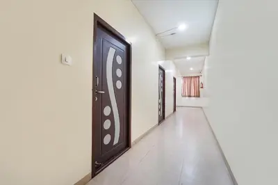 a hallway with black doors and white walls at FabHotel Manis Residency in Coimbatore