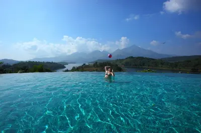 a woman playing with a red ball in a pool of water at Arayal Resort-A Unit of Sharoy Resort in Tariyod