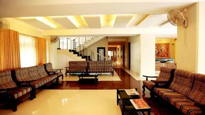 a living room with couches and a staircase at KTDC Garden House in Palakkad