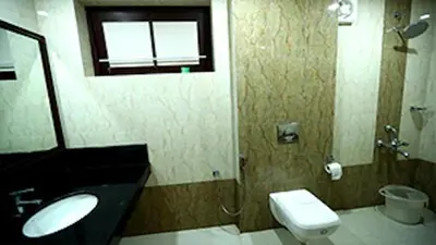 a bathroom with a sink and a toilet and a window at KTDC Garden House in Palakkad