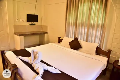 a hotel room with a bed with a towel on a table at mangosteen holidays in Vythiri