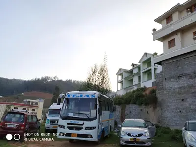 a bus and cars parked next to a building at A Ooty Honey Huts in Ooty