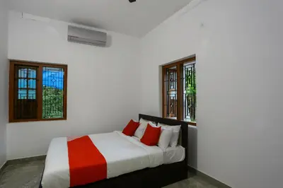 a white bedroom with a bed with red pillows at Hotel O Al Ameen Residency in Kannur