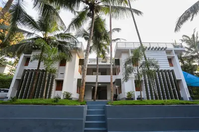 a building with palm trees in front of it at Hotel O Al Ameen Residency in Kannur