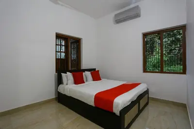 a bedroom with a bed with red and white pillows at Hotel O Al Ameen Residency in Kannur