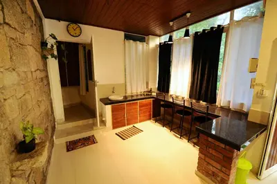 a kitchen with a counter and chairs in a room at Aruvi homestay in Vythiri