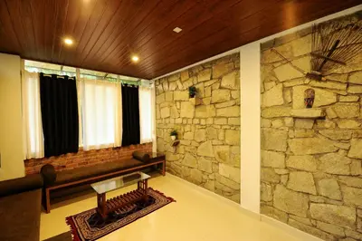 a living room with a stone wall and a bench at Aruvi homestay in Vythiri