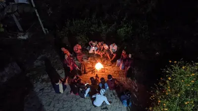 a group of people standing around a fire at night at Chamayam Holiday Villa in Meenangadi