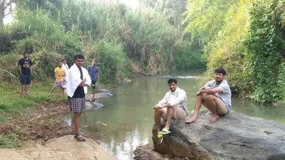 a group of men sitting on a rock near a river at Chamayam Holiday Villa in Meenangadi