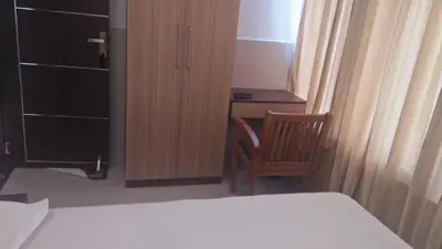 a bedroom with a bed and a desk and a chair at LEMON RESIDENCY By Chungath in Trichūr