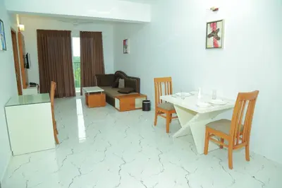 a living room with a couch and a table and chairs at Utsavam Hotel Apartments in Guruvāyūr