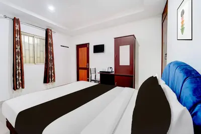 a bedroom with a large bed with a blue blanket at Super Hotel O Kunnamangalam Near Bus Stand in Calicut