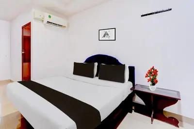 a bedroom with a large bed and a table at Super Hotel O Kunnamangalam Near Bus Stand in Calicut