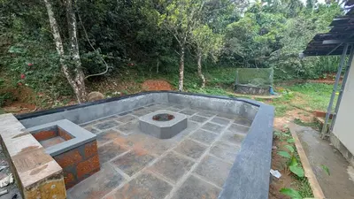 a concrete patio with a fire pit in a backyard at Caffeine Villa in Kaniyāmbetta