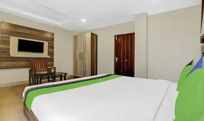a bedroom with a bed and a chair and a television at Treebo Darwesh Residency - 500m from Railway Station in Kozhikode