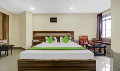 a bedroom with a large bed and two chairs at Treebo Darwesh Residency - 500m from Railway Station in Kozhikode