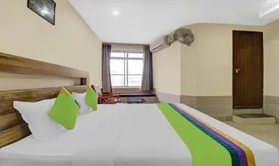 a bedroom with a large white bed with green pillows at Treebo Darwesh Residency - 500m from Railway Station in Kozhikode