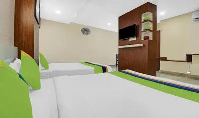 a bedroom with two white beds and a tv at Treebo Darwesh Residency - 500m from Railway Station in Kozhikode