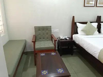 a room with a bed and a chair and a table at Green Planet Resort in Mattanūr