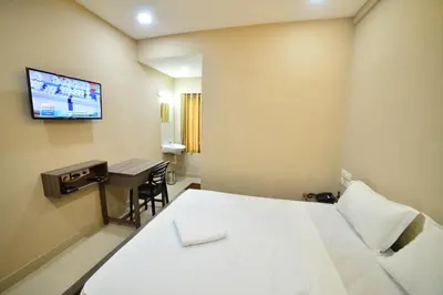 a room with a bed and a desk and a tv at Hotel Priya in Kottakkal