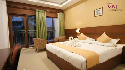 a hotel room with a bed and a window at Hotel VKJ International Kuttampuzha in Thattakād