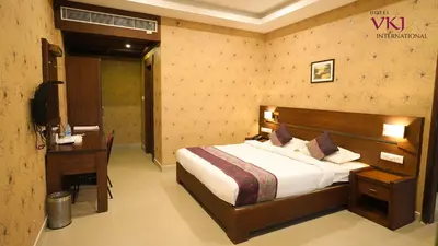 a bedroom with a bed and a desk and a television at Hotel VKJ International Kuttampuzha in Thattakād
