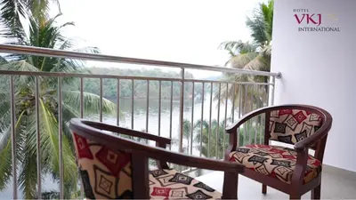a balcony with a chair and a view of the ocean at Hotel VKJ International Kuttampuzha in Thattakād