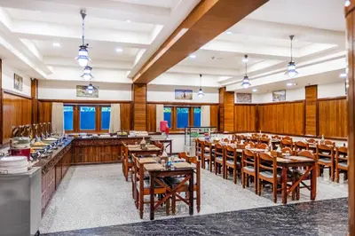a restaurant with wooden walls and tables and chairs at Sterling Darshan Guruvayur in Guruvāyūr