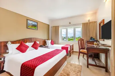 a hotel room with two beds and a desk and a television at Sterling Darshan Guruvayur in Guruvāyūr