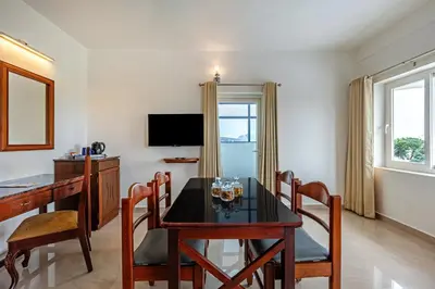 a dining room with a table and chairs and a television at Sterling Darshan Guruvayur in Guruvāyūr