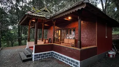 a small building with a porch and stairs in a forest at 900 Woods Wayanad Eco Resort - A Sprawling Jungle Stay near Glass Bridge in Meppādi