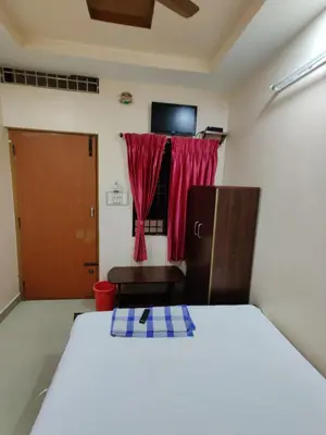 a bedroom with a bed and a window with a red curtain at Sakthimurugan residency in Erode