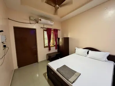 a bedroom with a large white bed and a door at Sakthimurugan residency in Erode