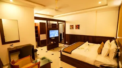 a bedroom with a bed and a desk and a television at Hotel Emperor in Kannur