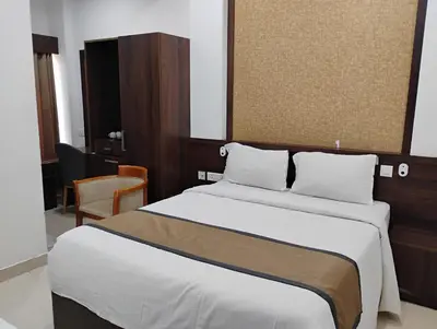 a hotel room with a bed and a chair at Hotel Emperor in Kannur