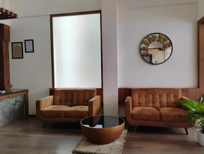 a living room with two couches and a mirror at Hotel Emperor in Kannur