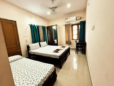 a room with two beds and a table in it at Thrissur Villas Home Stay in Trichūr