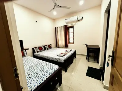a room with two beds and a desk in it at Thrissur Villas Home Stay in Trichūr