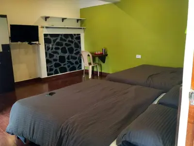 a bedroom with two beds and a table and a window at The Meadows in Kodaikānāl