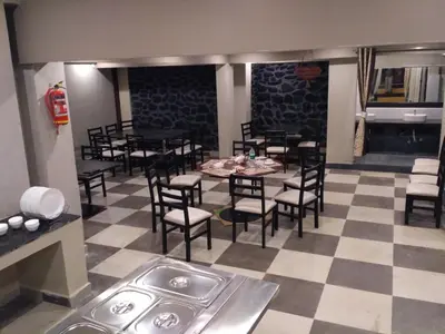 a restaurant with tables and chairs on a checkered floor at The Meadows in Kodaikānāl