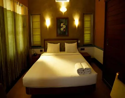 a bedroom with a bed with two towels on it at Chembra Adobe in Kalpetta