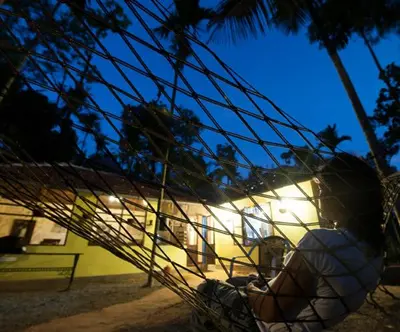 a person sitting in a net in front of a building at Grassroots Wayanad, Valley-view Tents in Vythiri