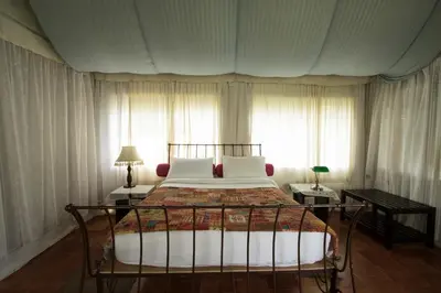 a bedroom with a bed with white pillows and a window at Grassroots Wayanad, Valley-view Tents in Vythiri
