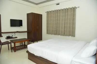 a bedroom with a bed and a desk and a television at Grand Misty Heaven in Madikeri