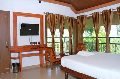 a bedroom with a bed and a desk and a television at KINGMAKER'S Plantation with River Stream in Madikeri