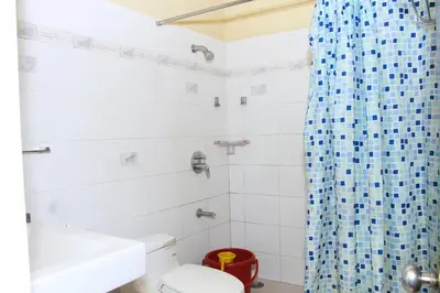 a bathroom with a blue shower curtain and a toilet at KINGMAKER'S Plantation with River Stream in Madikeri