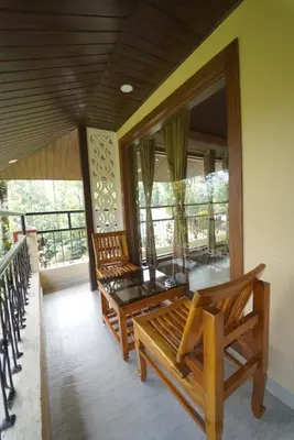 two wooden benches sitting on a balcony with windows at KINGMAKER'S Plantation with River Stream in Madikeri