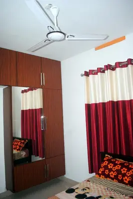 a bedroom with a ceiling fan and a red curtain at NICE VILLA in Irimbranallūr