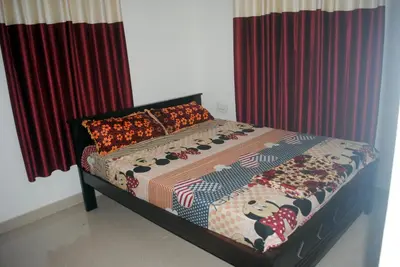 a bed in a bedroom with red curtains at NICE VILLA in Irimbranallūr